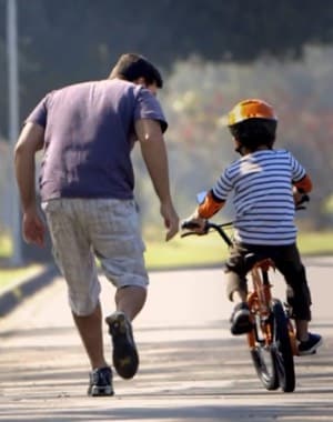 Pai ensinando o filho a andar de bicicleta